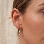 Gold crystal drop huggie hoop earring worn